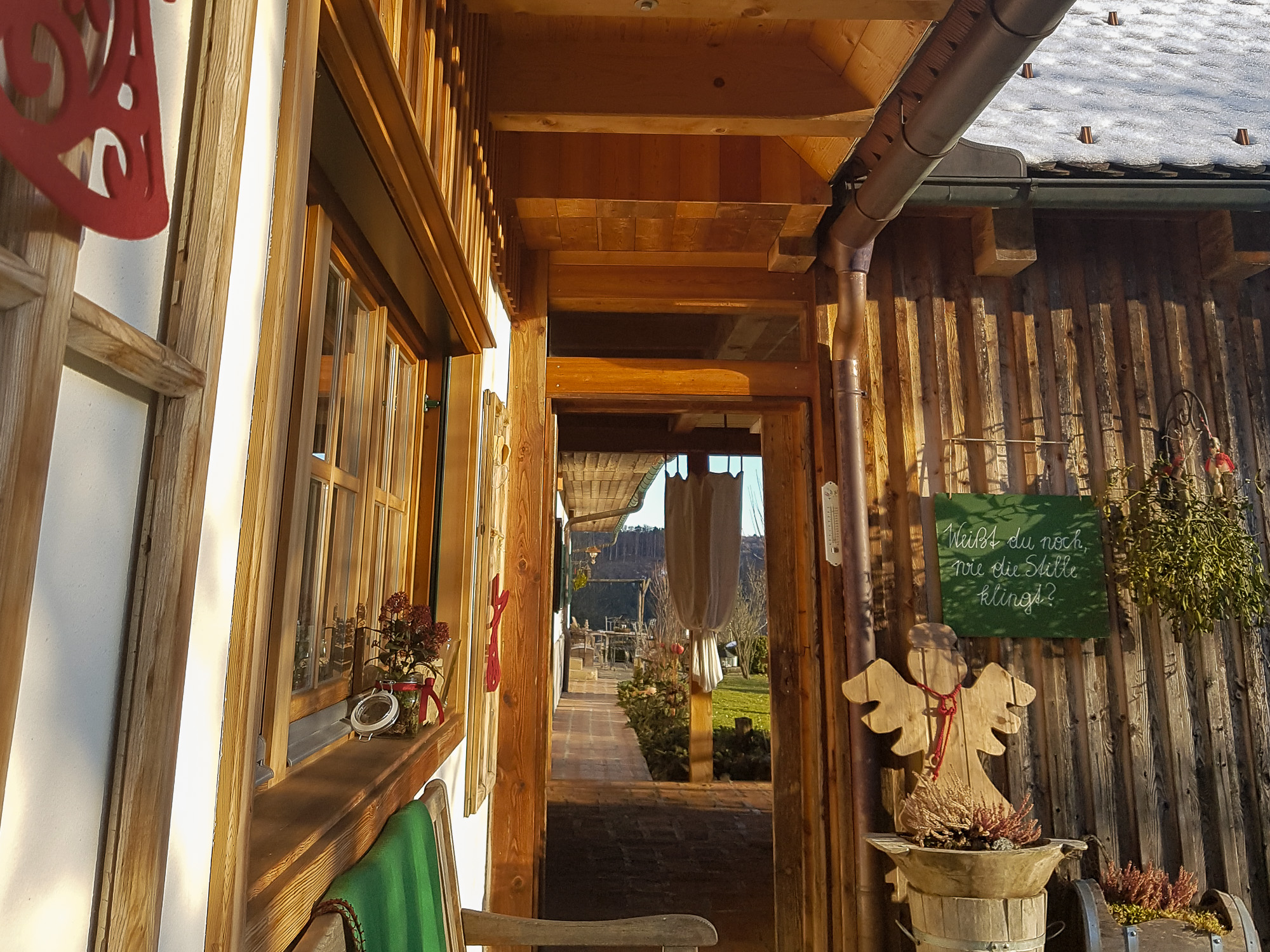 Blick durch Holztür in Innenhof, im Vordergrund steht ein hölzerner Engel