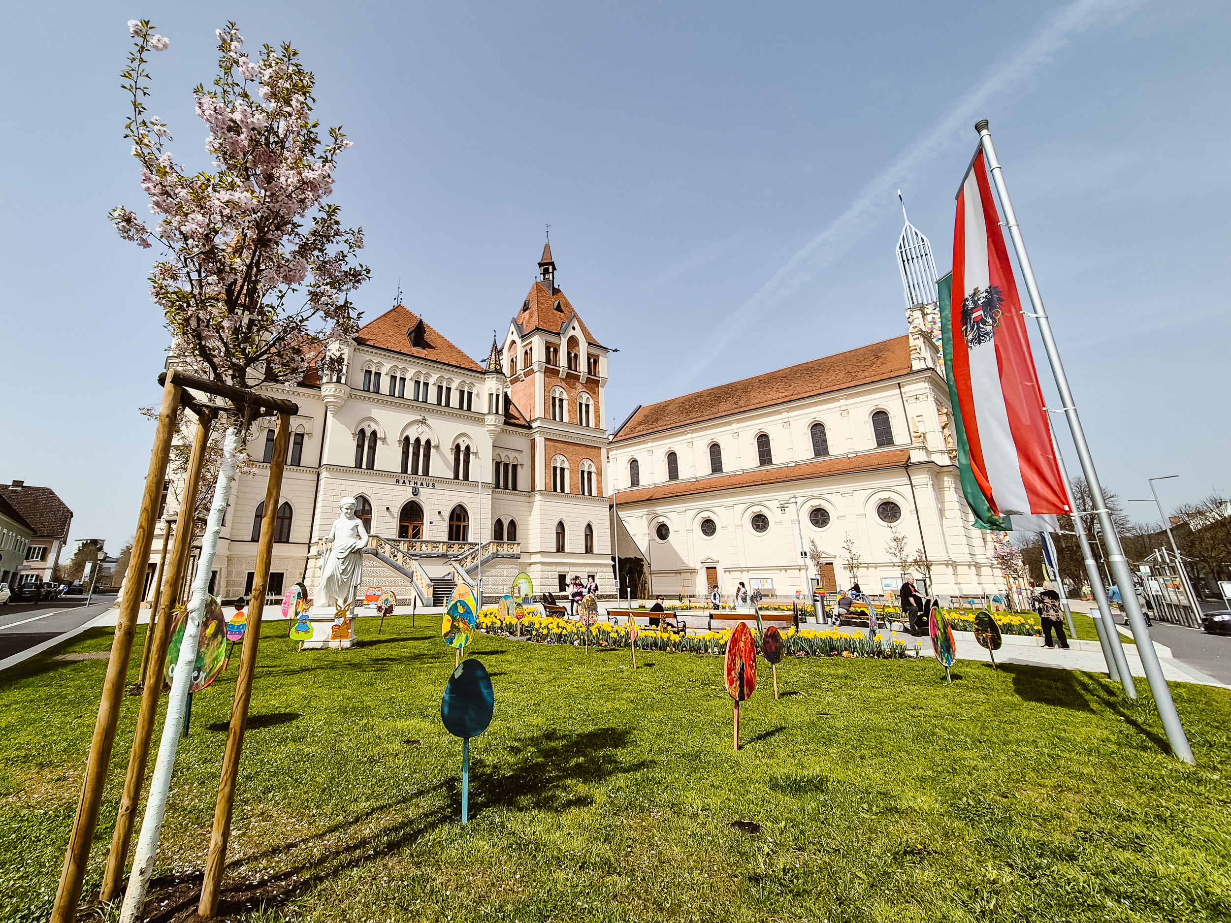 Bunt bemalte Ostereier aus Holz stecken in der Wiese vor dem Feldbacher Rathaus