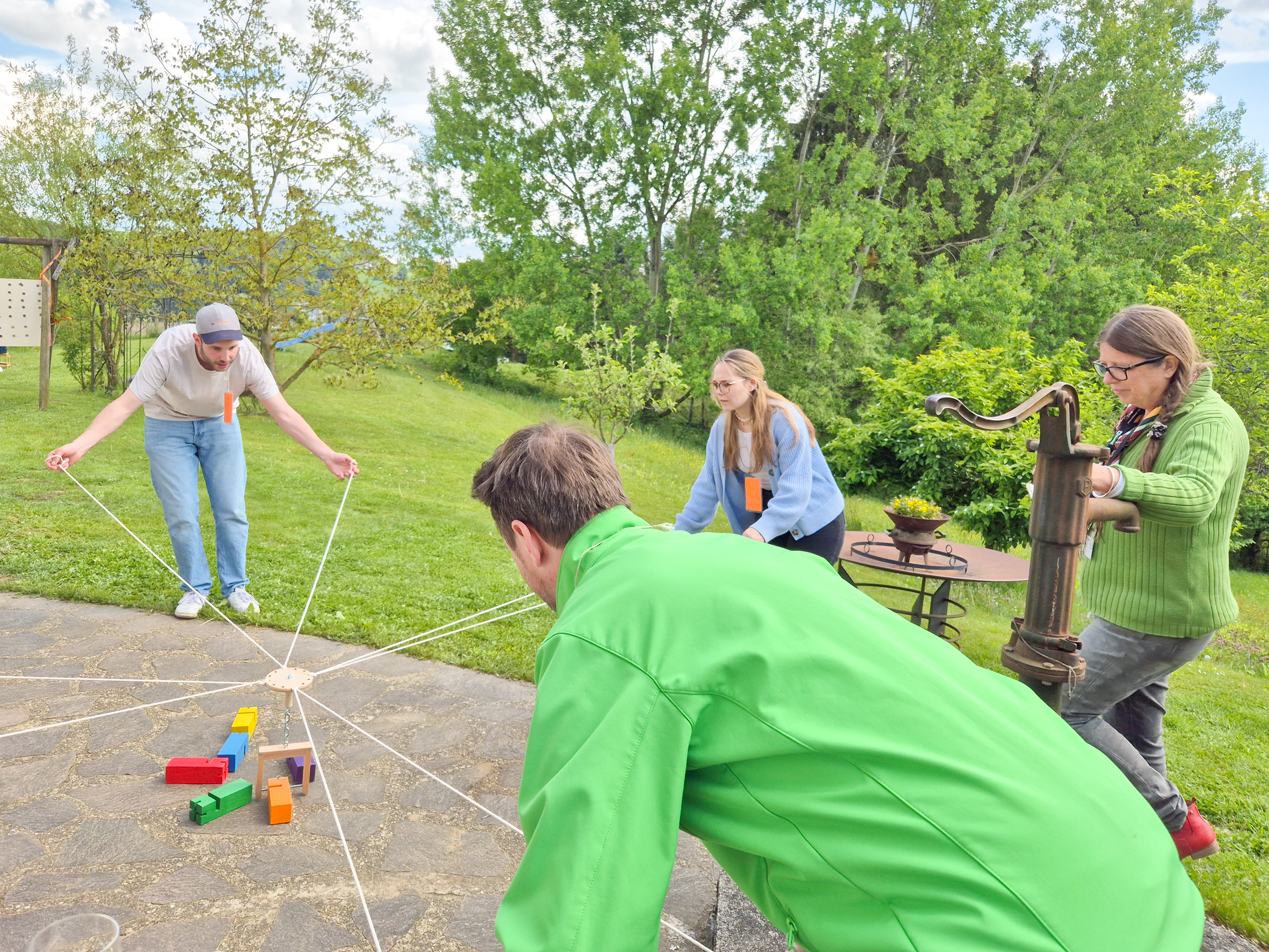 Four people attempt to build a tower from wooden blocks