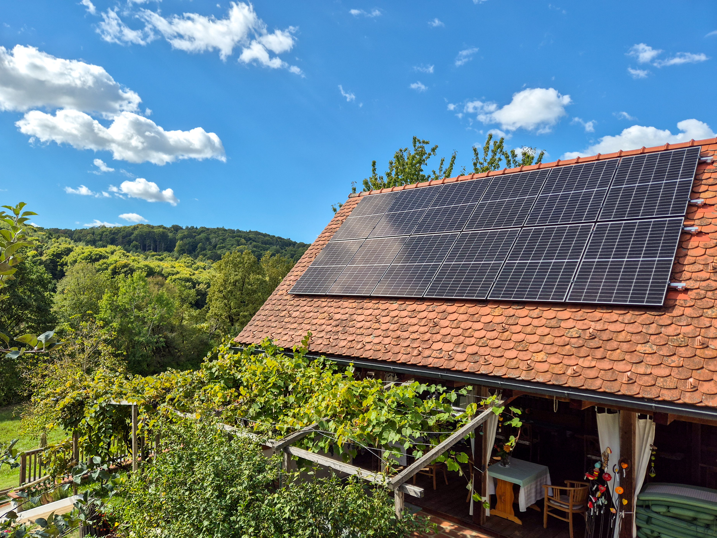Offener Aufenthaltsbereich in einem Holzbau mit rotem Ziegeldach und Photovoltaik-Zellen