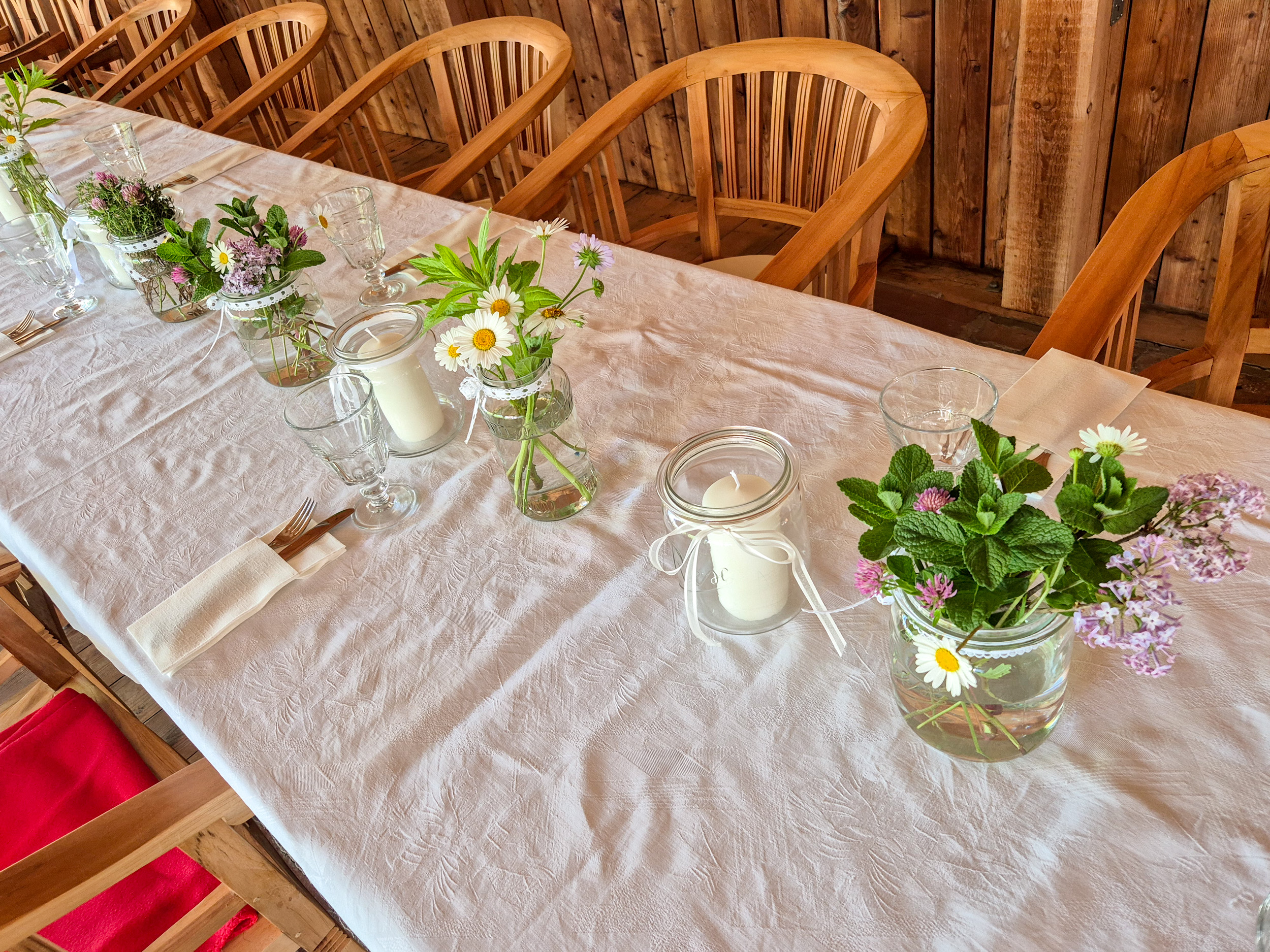 Flowers and candles are arranged on a white tablecloth, with cutlery set out