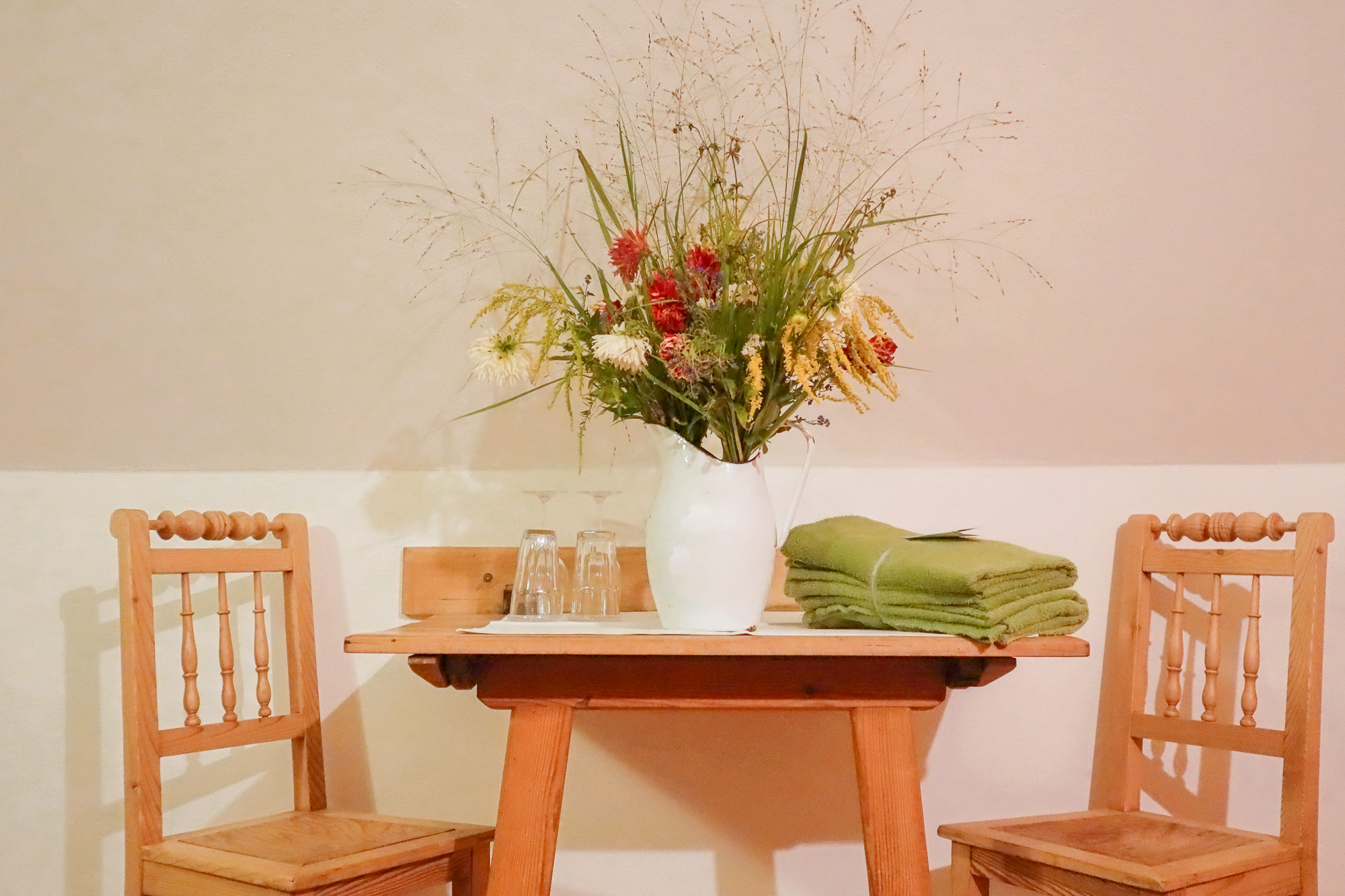 Tisch mit Blumen, Stühlen daneben und Tüchern für den Garten in der Landhaus-Suite Kräuterduft