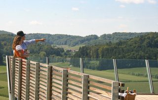 Junges Paar mit Picknickkorb auf einer Aussichtsplattform in grüner Natur